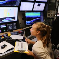 Artist-At-Sea participant Lauren Salm monitors incoming data from R/V Falkor's mulitbeam sonar.